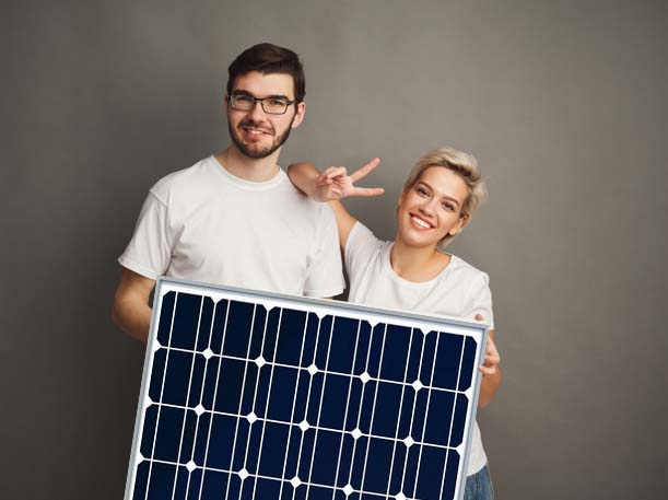 Junges Paar hält ein Photovoltaikmodul vor einem Wohnhaus
