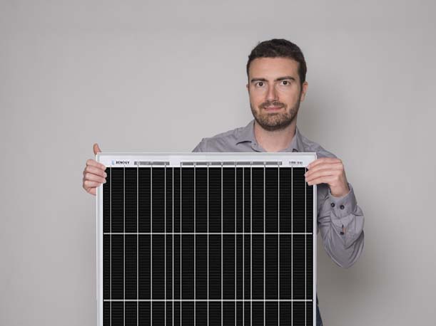 Mann mit Photovoltaikmodul vor blauem Himmel